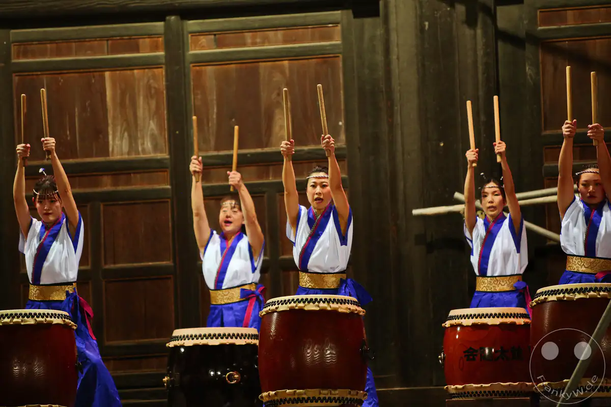 Fünf japanische Musikerinnen recken ihre Holzstöcke synchron in die Höhe, während sie eine feierliche Taiko-Trommelzeremonie am historischen Saidai-ji Kannon-in Tempel in Okayama vorführen.