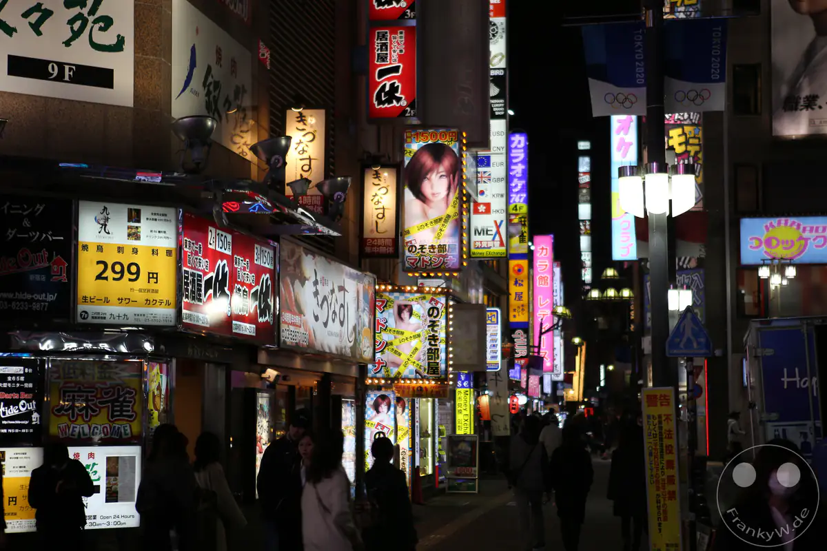 Belebte Fußgängerzone im Amüsierviertel Kabukicho bei Nacht mit leuchtenden Werbetafeln, Restaurant-Schildern und Passanten im Stadtteil Shinjuku in Tokio, Japan.