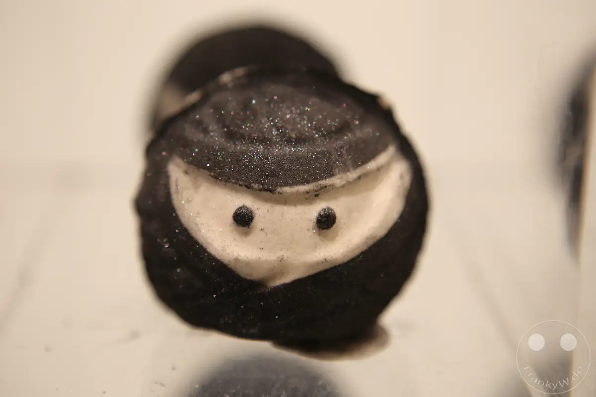 Eine Nahaufnahme einer handgemachten, runden Badebombe mit schwarzem Glitzer und Augenmotiv in Form eines traditionellen japanischen Ninja aus dem Sortiment des Kosmetikherstellers Lush in Tokio, Japan.