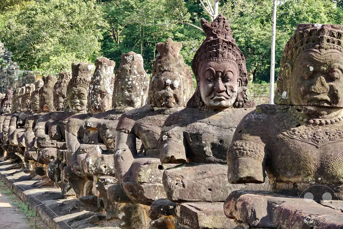 Eine Reihe steinerner Dämonenstatuen (Asuras) mit grimmigen Gesichtsausdrücken auf der Brücke vor dem Südtor von Angkor Thom in Kambodscha.
