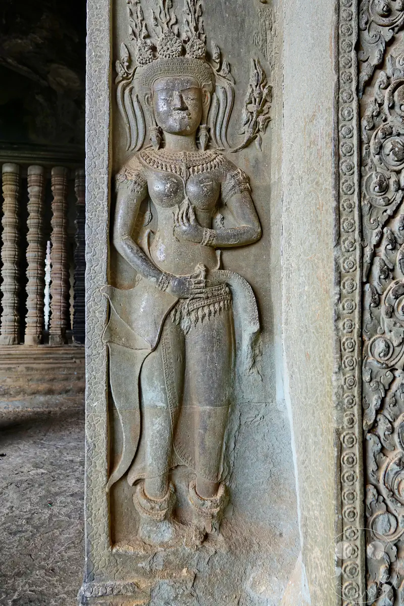 Ein detailreiches historisches Steinrelief einer tanzenden Apsara-Himmlersgöttin mit traditionellem Kopfschmuck und feinen Verzierungen an einem Steinpfeiler im Angkor-Wat-Tempel.