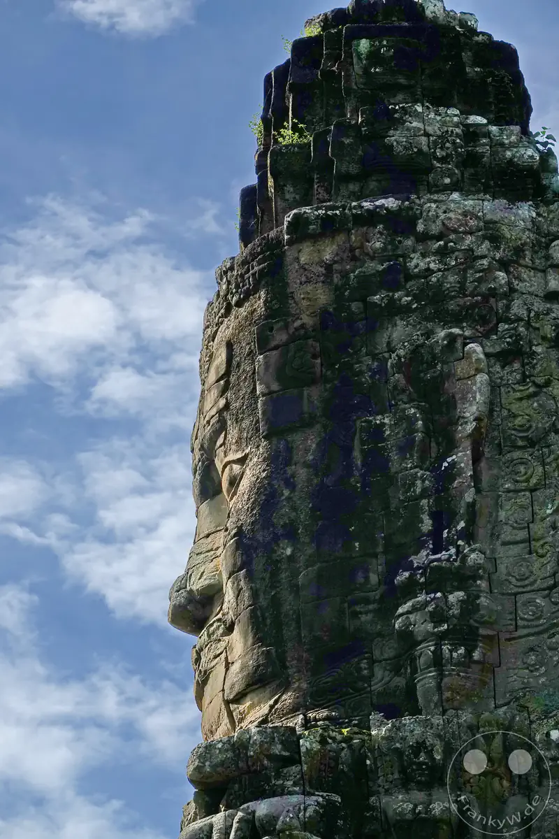 Seitenprofil eines monumentalen, in den Stein gemeißelten Gesichts im Bayon-Stil auf dem historischen Südtor der antiken Stadt Angkor Thom in Kambodscha vor blauem Himmel.