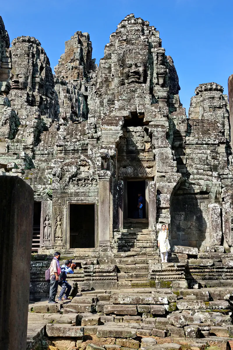 Besucher posieren für Fotos vor den historischen Steintürmen mit den markanten Gesichtern am Bayon-Tempel in Angkor Thom, Kambodscha.