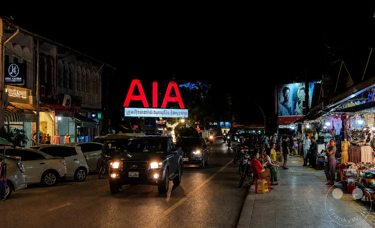 Nachtaufnahme aus Siem Reap mit Marktständen, Straßenverkehr und Leuchtreklame – das pulsierende Leben Kambodschas.