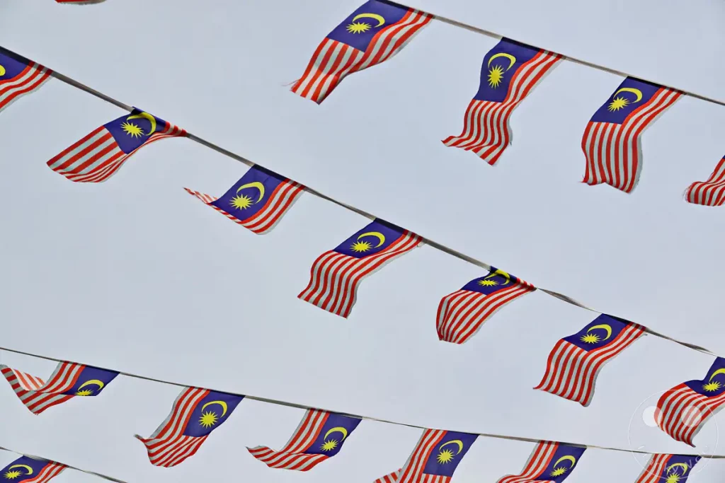 Zahlreiche kleine malaysische Flaggen hängen an Girlanden gespannt über einer historischen Straße in Malakka
