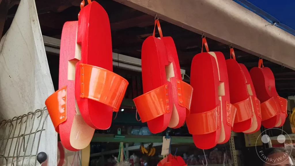 Mehrere Paare der traditionellen roten Holzschuhe (Terompah) hängen aufgereiht an einem Marktstand in der Stadt Melaka zum Verkauf.