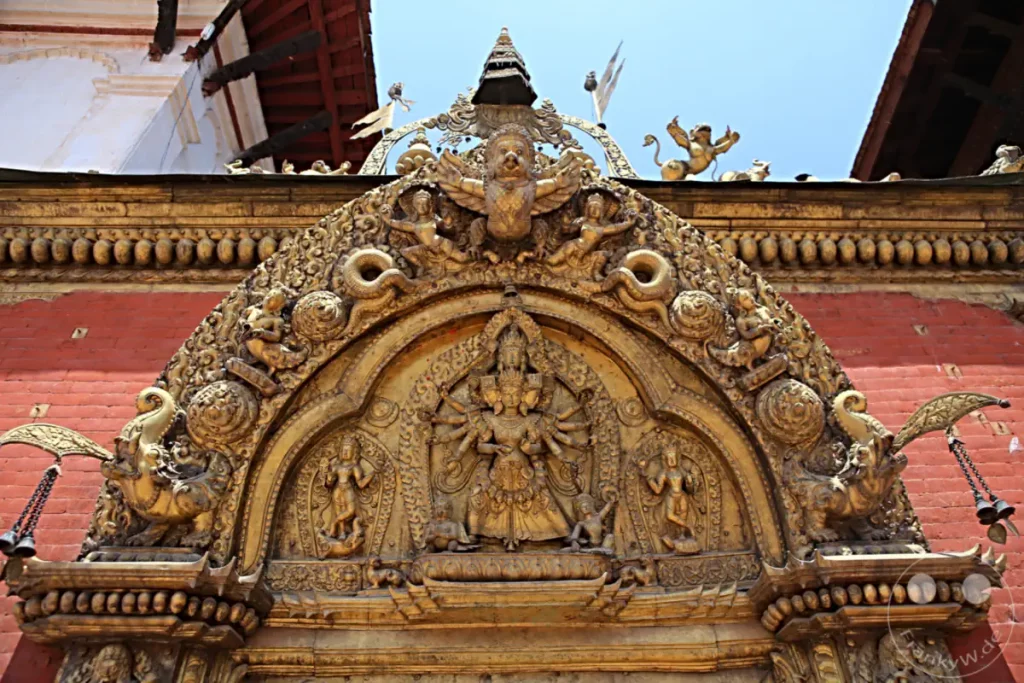 Ein detailliertes goldenes Schnitzwerk schmückt die Fassade eines Tempels in Bhaktapur, Nepal. Die kunstvollen Verzierungen zeigen mythologische Figuren und symbolische Darstellungen, die die reiche kulturelle und religiöse Geschichte der Region widerspiegeln.