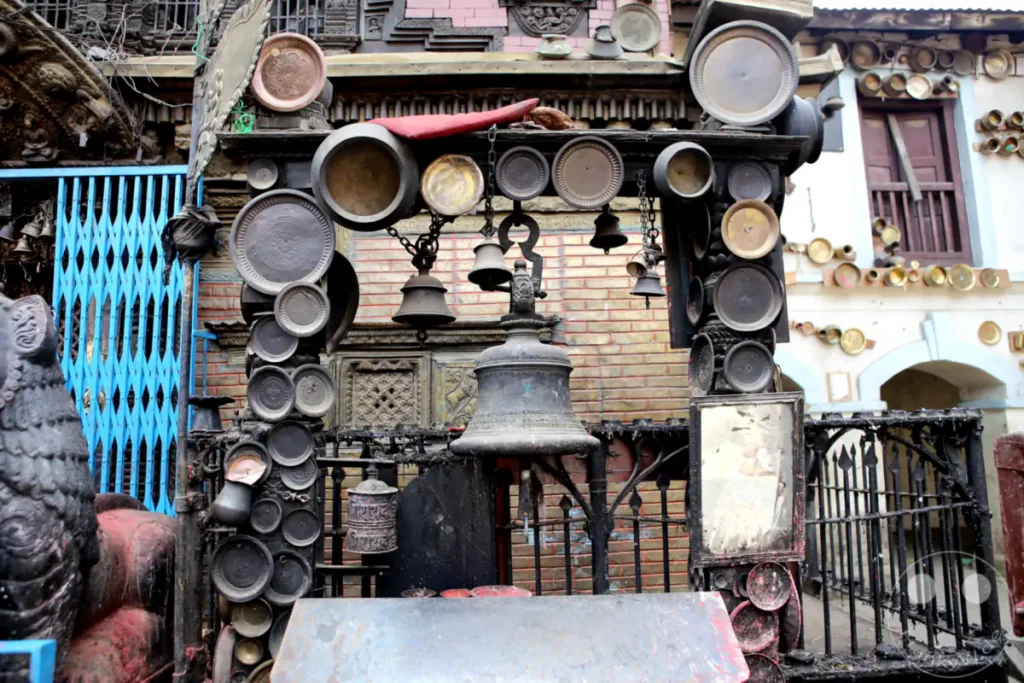Am Aanandadi Lokeshwar Tempel in Bhaktapur, Nepal, sind zahlreiche Bronzeglocken und verzierte Schalen ausgestellt. Die Anordnung der Kultgegenstände erzeugt eine Atmosphäre von Spiritualität und Tradition, typisch für die Tempelanlagen Nepals.