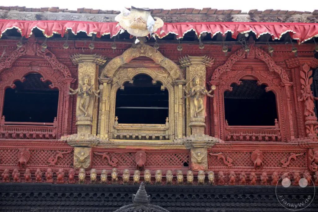 Das Bild zeigt kunstvolle Holzschnitzereien und Verzierungen an der Fassade eines Tempels am Kathmandu Durbar Square. Die aufwendige rote und goldene Gestaltung vermittelt einen Eindruck von reicher Kultur und spiritueller Bedeutung.