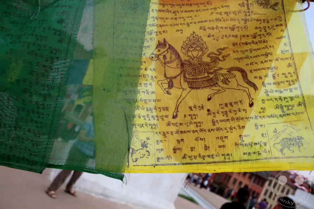 Bunte buddhistische Gebetsfahnen wehen im Wind vor der Boudhanath Stupa in Kathmandu. Die traditionellen Fahnen sind mit Mantras und Symbolen bedruckt und tragen zur spirituellen Atmosphäre des Ortes bei.