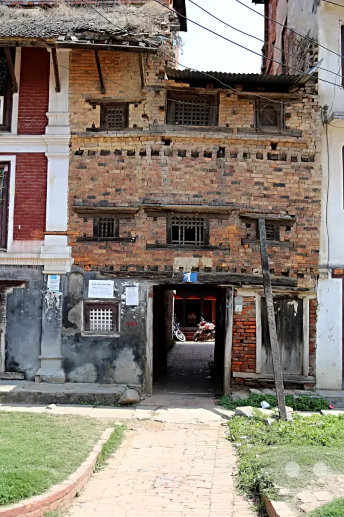 Ein Blick in den Innenhof des Hiranya Varna Mahavihar Klosters in Lalitpur, Nepal. Das Bild zeigt die architektonische Struktur eines traditionellen Gebäudes, das Anzeichen von Alter und Verfall aufweist, aber dennoch einen Einblick in die lokale Kultur und Geschichte bietet.