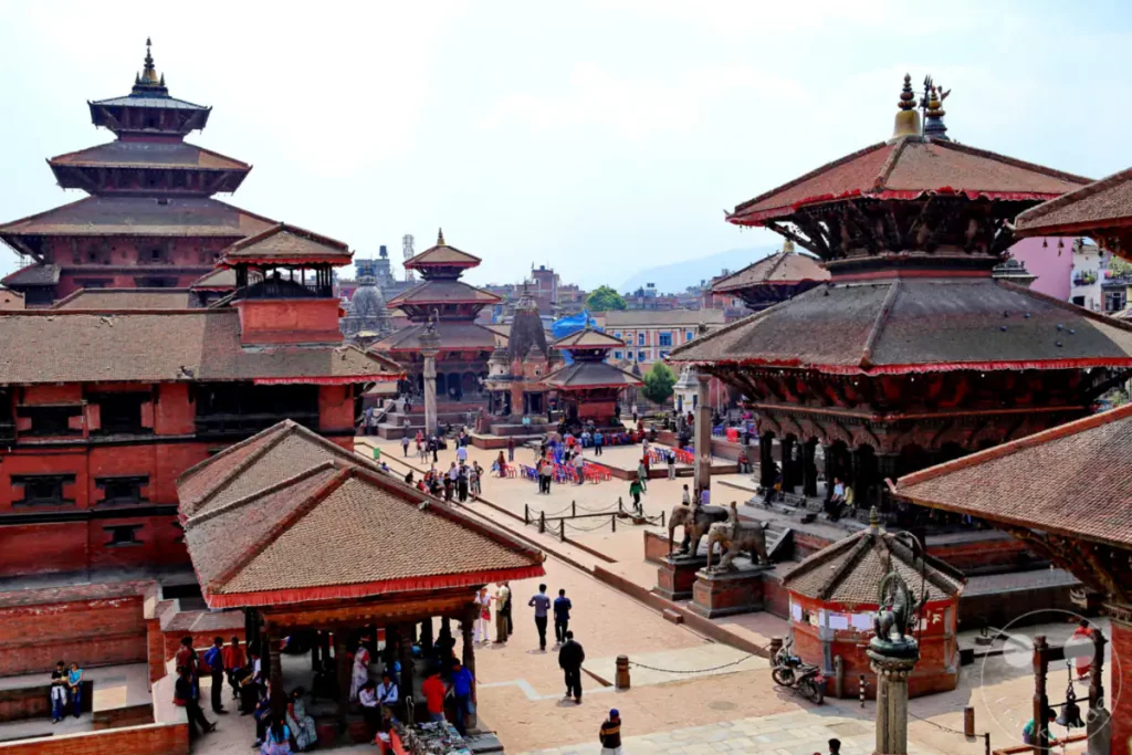 Blick über den Durbar Square in Bhaktapur, Nepal. Die historischen Tempel und Gebäude bilden eine beeindruckende Kulisse für das geschäftige Treiben auf dem Platz. Die Szene strahlt eine Mischung aus kulturellem Erbe und lebendiger Atmosphäre aus.