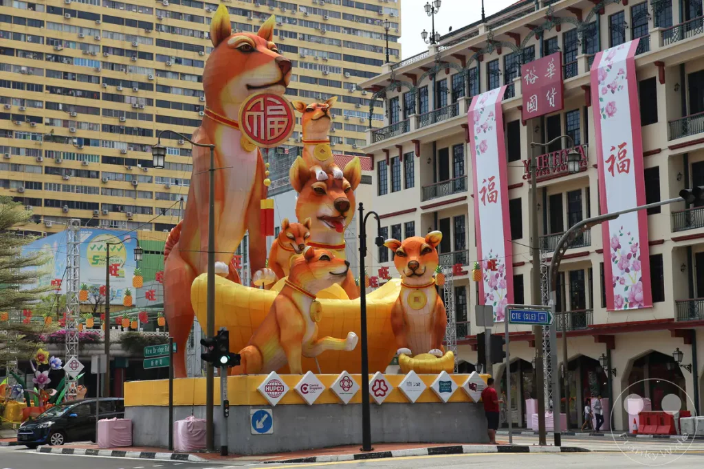 Ein Fest der Freude und Tradition im Herzen von Singapur, wo kunstvolle Hund-Laternen die Straßen von Chinatown während der Neujahrsfeiern schmücken. Bunte Dekorationen und die beeindruckende Architektur der Gebäude schaffen eine lebendige und festliche Atmosphäre. Die Szene fängt die Essenz des kulturellen Erbes und des Gemeinschaftsgeistes ein.
