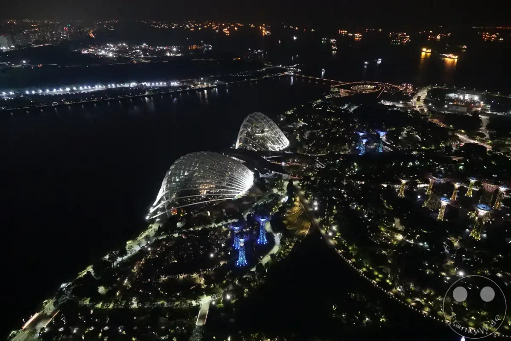 Die Gardens by the Bay in Singapur erstrahlen bei Nacht in einem magischen Licht. Die ikonischen Supertrees und die Gewächshäuser, Flower Dome und Cloud Forest, werden von tausenden Lichtern angestrahlt. Die Szenerie bietet einen atemberaubenden Ausblick auf die futuristische Architektur inmitten des urbanen Dschungels.