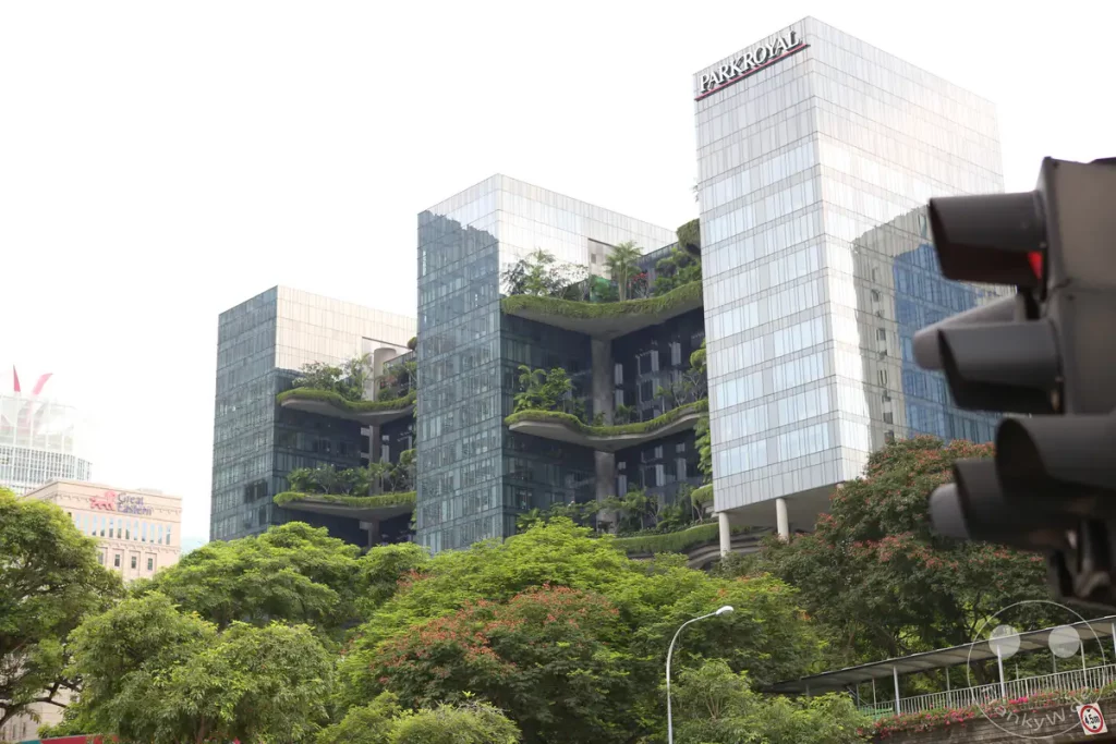 Das Bild zeigt das markante Parkroyal Hotel in Singapur, bekannt für seine "Sky-Gardens" und nachhaltige Architektur. Die üppige Vegetation, die sich über die Terrassen erstreckt, hebt sich vom modernen Glas- und Stahlbau ab und schafft eine harmonische Verbindung von Natur und Stadt. Die Aufnahme vermittelt eine ruhige und gleichzeitig lebendige Atmosphäre inmitten der urbanen Dichte.