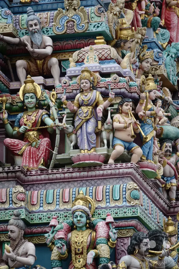 Detaillierte farbenfrohe Skulpturen schmücken die Fassade eines Hindu-Tempels in Singapur. Die kunstvollen Darstellungen zeigen mythologische Figuren und religiöse Szenen mit lebendigen Farben. Die Verzierungen strahlen eine reiche kulturelle und spirituelle Atmosphäre aus.