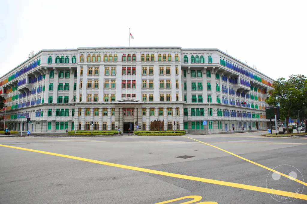 Das Bild zeigt ein beeindruckendes Gebäude in Singapur, das für seine bunten Fensterläden bekannt ist und mit seiner historischen Architektur beeindruckt. Die farbenfrohe Gestaltung verleiht dem sonst klassischen Bauwerk einen modernen und lebendigen Charakter. Die Szenerie strahlt eine Mischung aus Tradition und lebendiger Kultur aus.