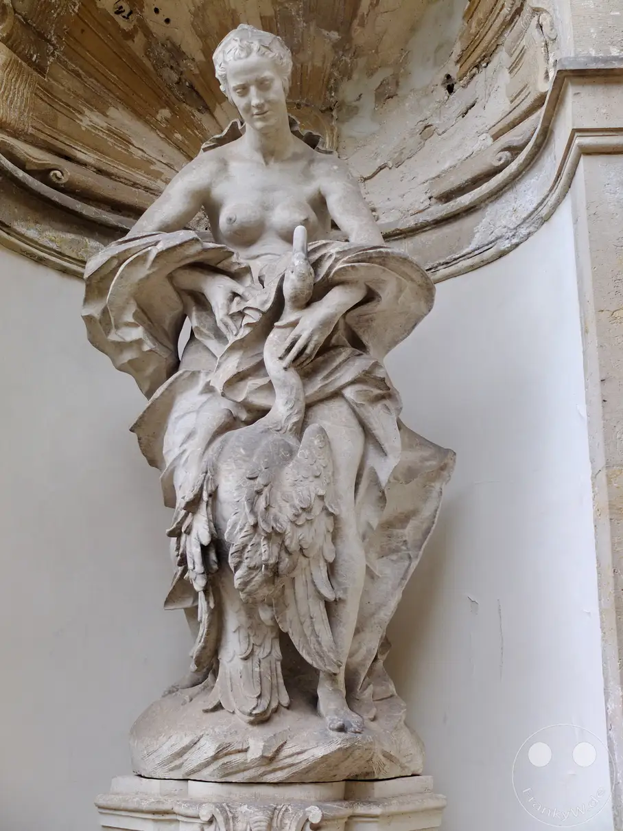 Eine detailreiche Skulptur aus Stein stellt die mythologische Figur Leda dar, die eine zarte Verbindung mit einem Schwan eingeht. Die Darstellungsweise der Figuren und die Draperien des Gewandes zeugen von kunstfertiger Handwerkskunst und vermitteln eine sinnliche und zugleich entrückte Atmosphäre im Dresdner Zwinger. Das Nymphenbad bietet eine prachtvolle Kulisse für dieses antike Motiv.