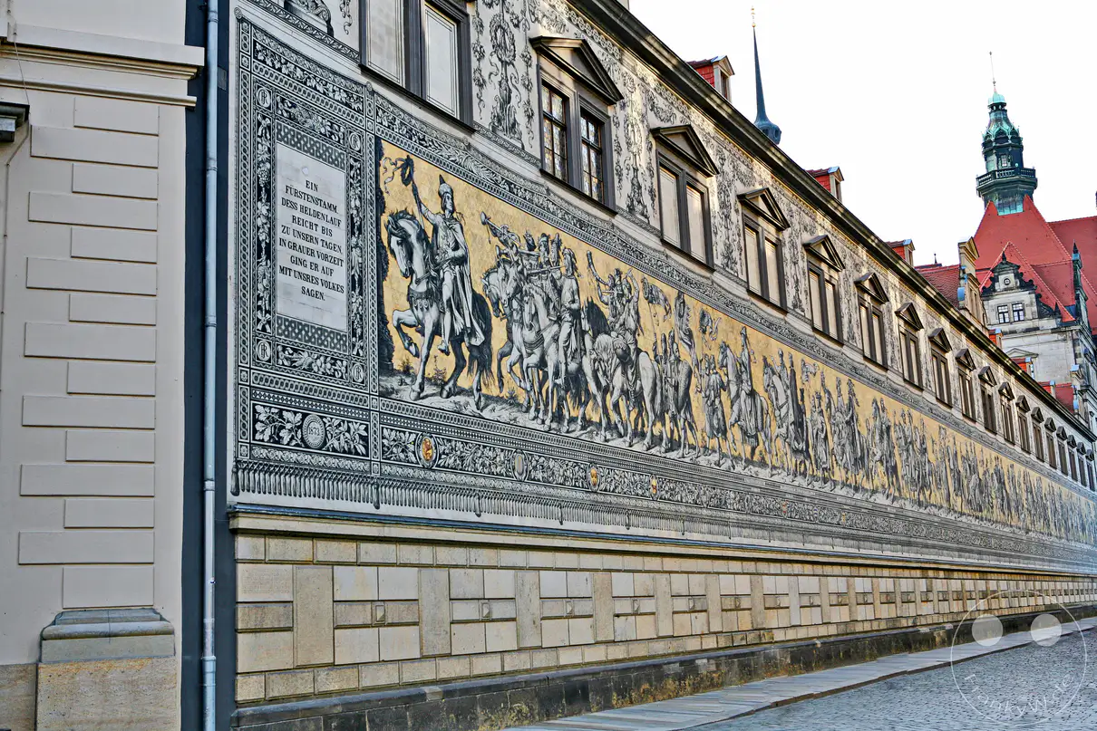 Der Fürstenzug in Dresden, Deutschland, ist das größte Porzellanwandbild der Welt und stellt eine majestätische Prozession der sächsischen Herrscher dar. Die detailreiche Darstellung auf Kacheln verbindet Kunst und Geschichte zu einem beeindruckenden Ensemble an der Außenwand des Stallhofs. Die Szene strahlt eine feierliche und historische Atmosphäre aus, die die Bedeutung der sächsischen Geschichte widerspiegelt.