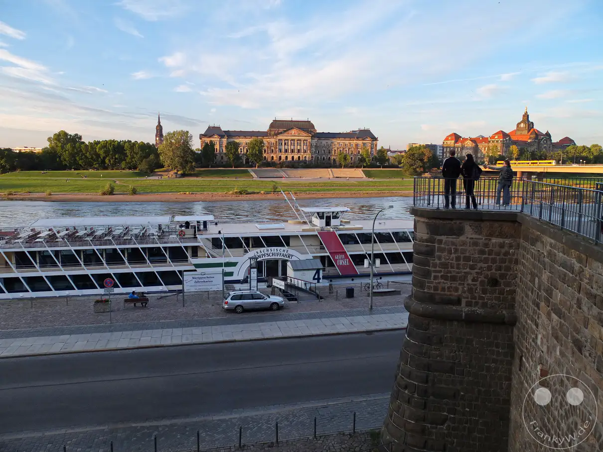 Der Abendhimmel spannt sich �ber Dresden, wo die Br�hlsche Terrasse einen Blick auf die Elbe und die historische Dampfschifffahrt freigibt. Am Ufer liegt das Fahrgastschiff �Gr�fin Cosel�, w�hrend im Hintergrund das imposante Geb�ude des S�chsischen Staatsministeriums der Finanzen die Kulisse bildet. Die ruhige Atmosph�re des Sonnenuntergangs wird durch die vorbeifliegenden M�wen und die sp�rlichen Wolken am Himmel unterstrichen.
