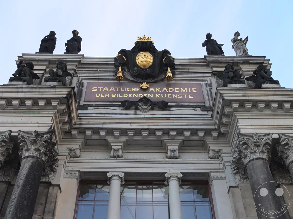 Die pr�chtige Fassade der Hochschule f�r Bildende K�nste in Dresden, Deutschland, ist geschm�ckt mit kunstvollen Skulpturen und Inschriften. Vergoldete Schriftz�ge und antike S�ulen zeugen von der historischen Bedeutung des Geb�udes. Die klare Himmelkulisse hebt die architektonische Pracht und die k�nstlerische Atmosph�re dieser renommierten Institution hervor.