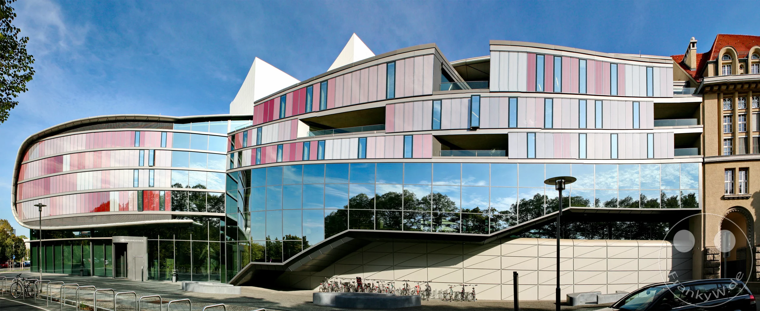 Der moderne vierte Erweiterungsbau der Deutschen Nationalbibliothek glänzt mit einer geschwungenen Glasfassade, die optisch der Bewegung eines Buchumschlags nachempfunden ist. Er verbindet die älteren Gebäudeteile zu einem geschlossenen Gesamtkomplex.