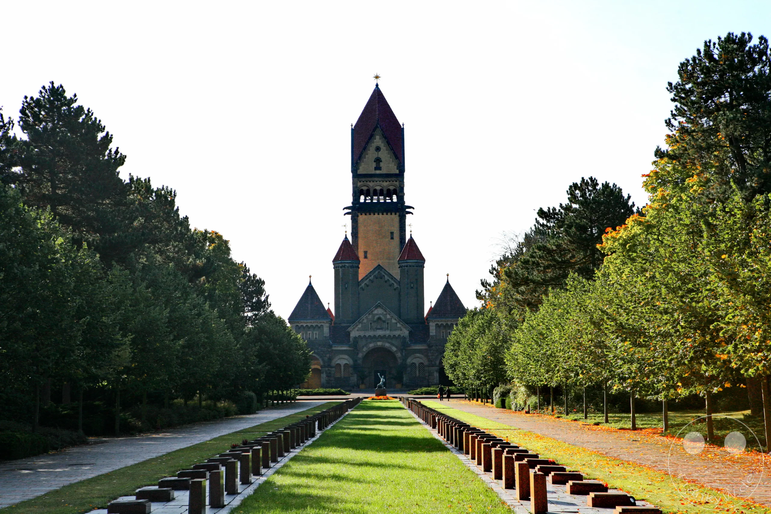 Der Südfriedhof in Leipzig präsentiert sich im Herbst mit einer eindrucksvollen Allee, die zu einem imposanten Mausoleum führt. Bunte Blätter bedecken den Wegesrand und die Rasenflächen, während die Bäume in warmen Tönen leuchten und eine friedliche Atmosphäre schaffen. Diese historische Anlage vereint architektonische Pracht mit der Schönheit der Natur.