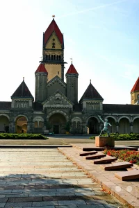 Eine Aufnahme des Leipziger Südfriedhofs mit seinem imposanten Denkmal und der beeindruckenden Architektur des Mausoleums. Die Szene strahlt eine würdevolle und zugleich nachdenkliche Atmosphäre aus, die durch die Skulptur und die umliegende Grünanlage unterstrichen wird. Dieser Parkfriedhof in Deutschland ist ein Ort der Ruhe und Erinnerung.