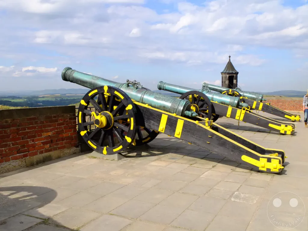 Mehrere historische Belagerungskanonen stehen auf dem gepflasterten Plateau der Festung Königstein in der Sächsischen Schweiz, Deutschland. Die schweren Geschütze sind auf die weite Landschaft ausgerichtet, die sich unterhalb der Festungsmauer erstreckt. Der sonnige Tag mit vereinzelten Wolken unterstreicht die imposante und geschichtsträchtige Atmosphäre dieses Ortes.