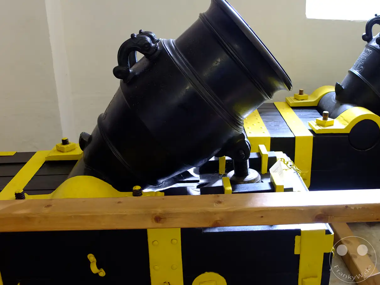 Imposante historische Mörser, liebevoll restauriert und ausgestellt im Alten Zeughaus der Festung Königstein in der Sächsischen Schweiz, Deutschland. Die robusten Exponate auf ihren auffälligen gelb-schwarzen Lafetten zeugen von vergangenen militärischen Epochen. Eine beeindruckende Darstellung der Wehrhaftigkeit vergangener Zeiten inmitten eines historischen Museums.
